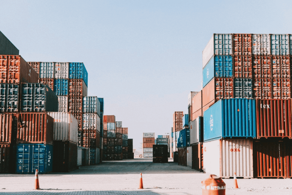 Stacks of shipping containers under clear sky.