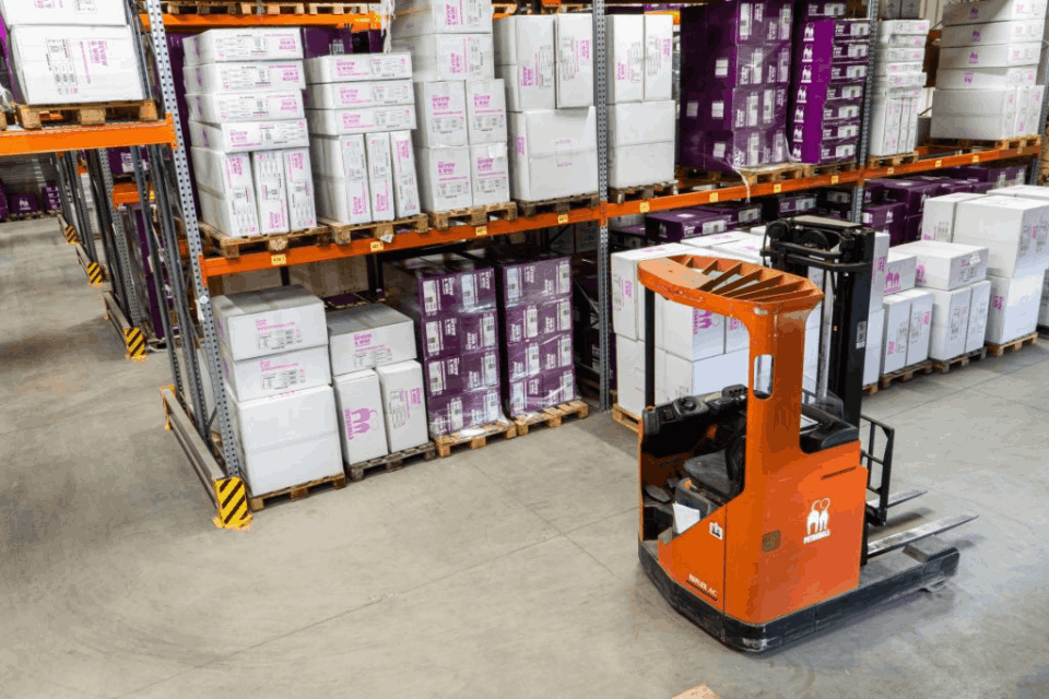 Forklift in a warehouse surrounded by boxes.